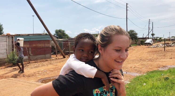 A worldwide medical insurance member giving a child a piggy-back ride across the street